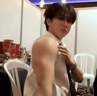 A Man In A White Shirt And Tie Is Adjusting His Tie In A Room . GIF