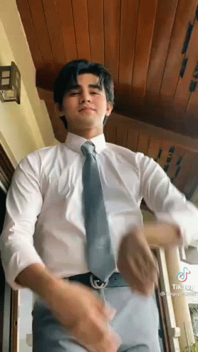 A Man In A White Shirt And Tie Is Dancing In A Room . GIF