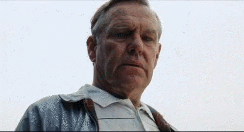 A Man In A White Shirt And Tie Is Looking At The Camera With A Serious Look On His Face . GIF