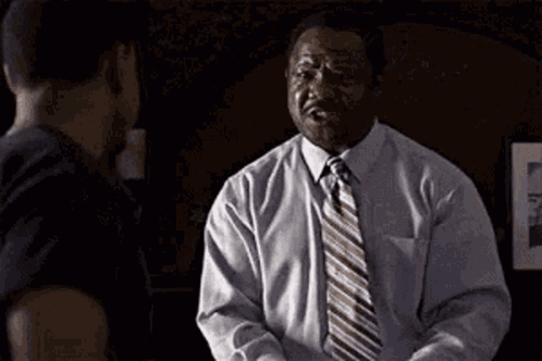 A Man In A White Shirt And Tie Is Shaking Hands With Another Man And Says She . GIF