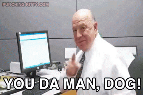 A Man In A White Shirt And Tie Is Sitting At A Desk In Front Of A Computer And Says You Da Man Dog . GIF