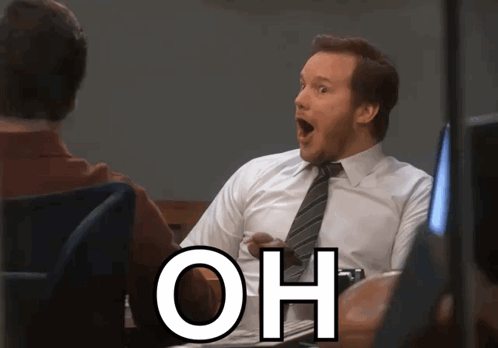 A Man In A White Shirt And Tie Is Sitting At A Desk With His Mouth Open And The Word Oh Written Below Him GIF