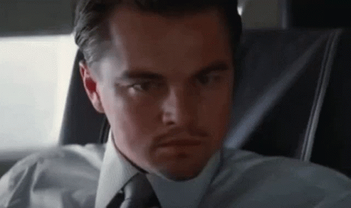 A Man In A White Shirt And Tie Is Sitting In A Car . GIF