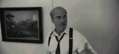 A Man In A White Shirt And Tie Is Standing In Front Of A Painting . GIF