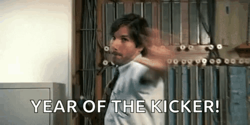 A Man In A White Shirt And Tie Is Standing In Front Of A Wall And Says `` Year Of The Kicker '' . GIF