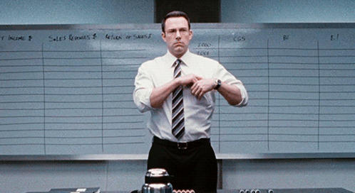 A Man In A White Shirt And Tie Is Standing In Front Of A White Board That Says Sales Revenues GIF