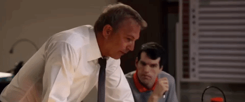 A Man In A White Shirt And Tie Is Standing Next To Another Man In A Room . GIF