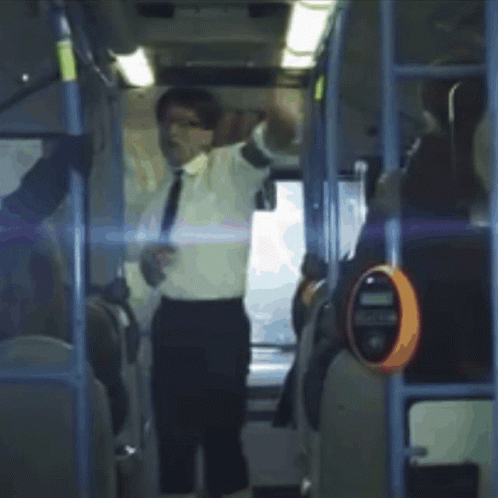 A Man In A White Shirt And Tie Is Standing On A Bus With His Arms Outstretched GIF
