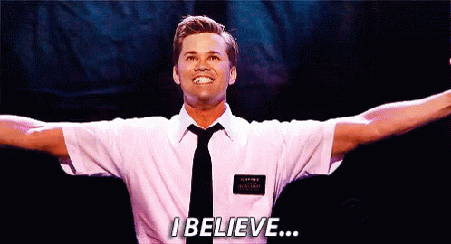 A Man In A White Shirt And Tie Is Standing On A Stage With His Arms Outstretched And Says I Believe . GIF