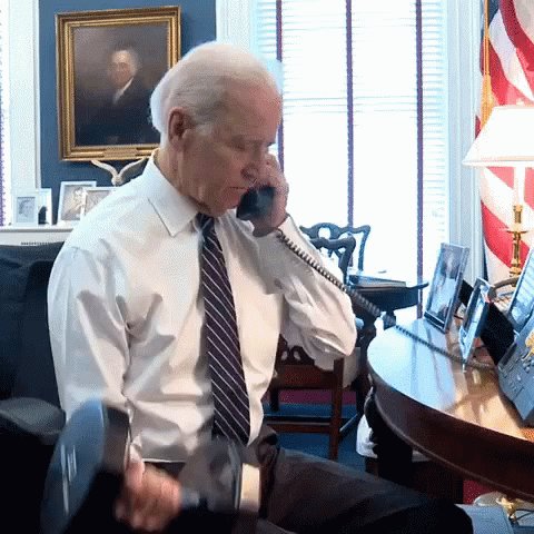 A Man In A White Shirt And Tie Is Talking On A Cell Phone GIF