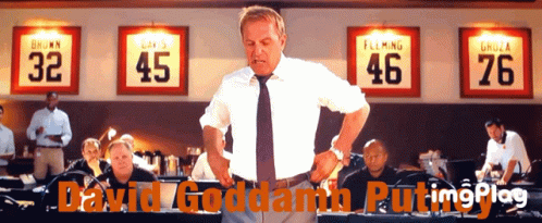A Man In A White Shirt And Tie Stands In Front Of A Row Of Jerseys With The Numbers 32 45 46 And 76 GIF