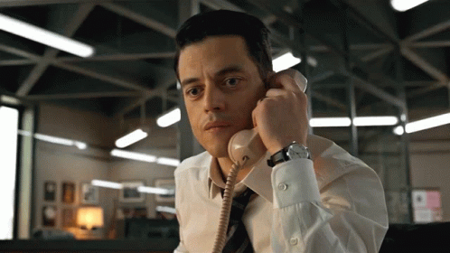 A Man In A White Shirt And Tie Talking On A Telephone GIF