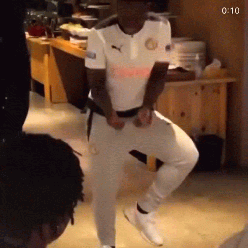 A Man In A White Shirt And White Pants Is Dancing In A Kitchen . GIF