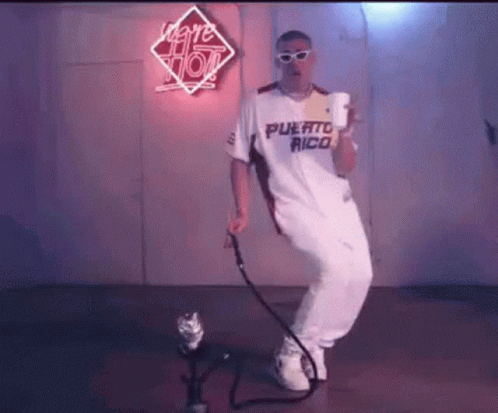 A Man In A White Shirt And White Pants Is Dancing In Front Of A Microphone . GIF