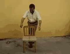 A Man In A White Shirt Is Carrying A Black Box On His Back GIF