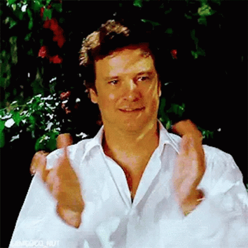 A Man In A White Shirt Is Clapping His Hands In Front Of A Tree . GIF