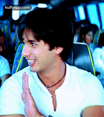 A Man In A White Shirt Is Clapping His Hands While Sitting On A Bus .. GIF