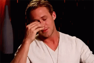 A Man In A White Shirt Is Covering His Face With His Hands . GIF