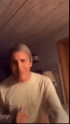 A Man In A White Shirt Is Dancing In A Dark Room . GIF
