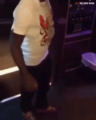A Man In A White Shirt Is Dancing In A Dark Room With The New Wave Written On The Bottom GIF