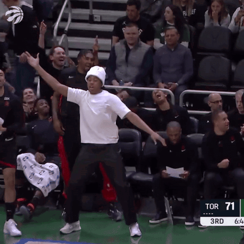 a man in a white shirt is dancing in front of a crowd at a sports game