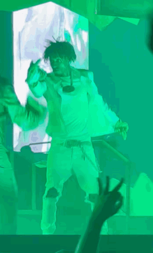 A Man In A White Shirt Is Dancing In Front Of A Green Screen GIF