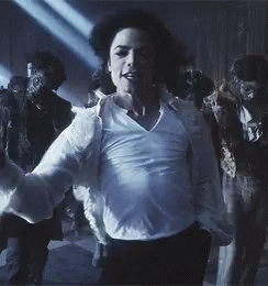 A Man In A White Shirt Is Dancing In Front Of A Group Of People In Costumes GIF
