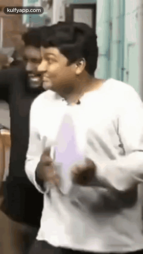 A Man In A White Shirt Is Dancing In Front Of A Man In A Black Shirt . GIF