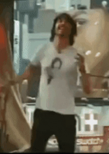 A Man In A White Shirt Is Dancing In Front Of A Swatch Sign . GIF