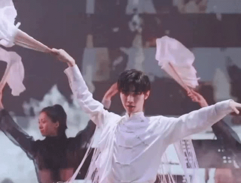 A Man In A White Shirt Is Dancing On A Stage With A Group Of Dancers . GIF