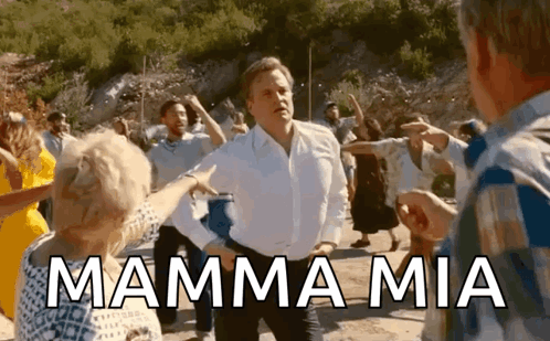 A Man In A White Shirt Is Dancing With A Group Of People And The Words Mamma Mia Are Written Above Him . GIF