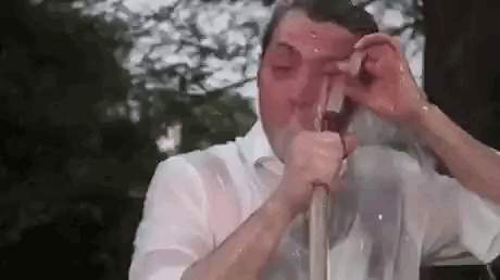 A Man In A White Shirt Is Drinking From A Hose . GIF