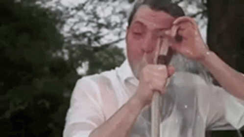 A Man In A White Shirt Is Drinking From A Straw . GIF