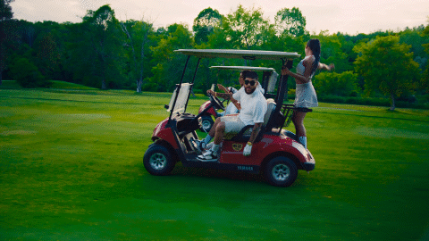 a man in a white shirt is driving a red yamaha golf cart