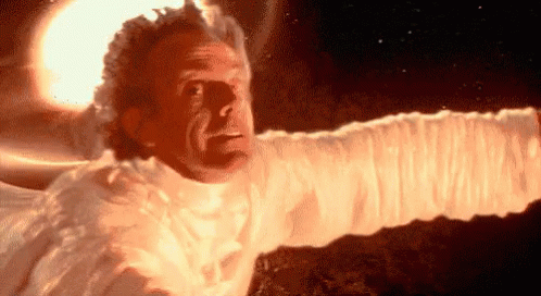 A Man In A White Shirt Is Flying Through The Air With His Arms Outstretched In Front Of A Bright Light . GIF