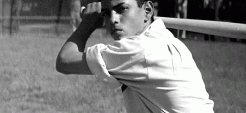 A Man In A White Shirt Is Holding A Baseball Bat Over His Head GIF