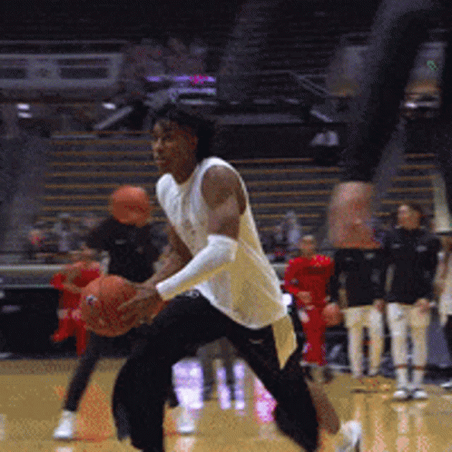 A Man In A White Shirt Is Holding A Basketball On A Court GIF