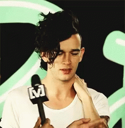 A Man In A White Shirt Is Holding A Microphone GIF