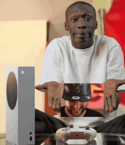 A Man In A White Shirt Is Holding A Picture Of A Man In A Hat GIF