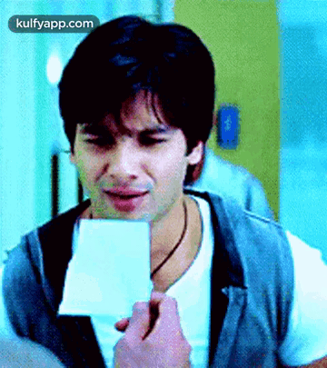 A Man In A White Shirt Is Holding A Piece Of Paper In His Hand . GIF