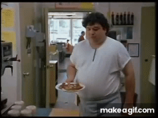 A Man In A White Shirt Is Holding A Plate Of Food In His Hand . GIF