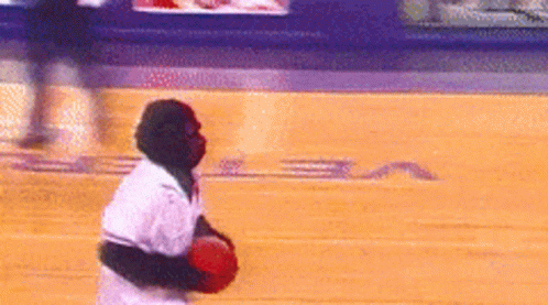 A Man In A White Shirt Is Holding A Red Ball On A Basketball Court With The Letter S On It GIF