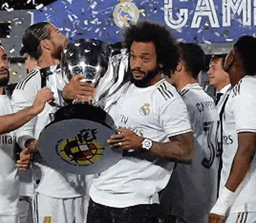 A Man In A White Shirt Is Holding A Trophy In Front Of A Group Of Soccer Players . GIF