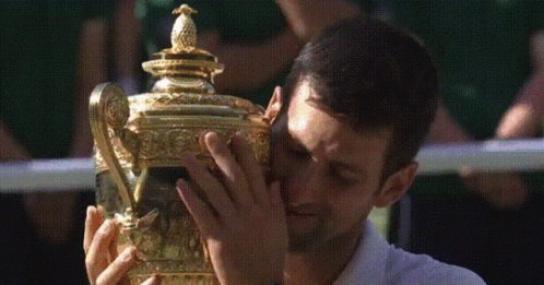 A Man In A White Shirt Is Holding A Trophy GIF