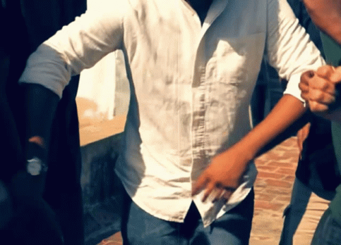 A Man In A White Shirt Is Holding Another Man 'S Hand GIF