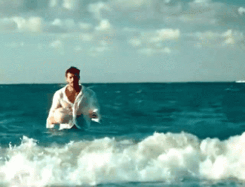 A Man In A White Shirt Is In The Ocean GIF