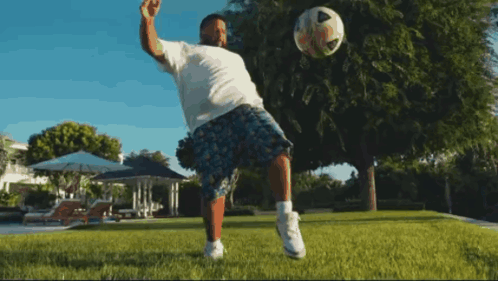 A Man In A White Shirt Is Kicking A Soccer Ball In The Air GIF