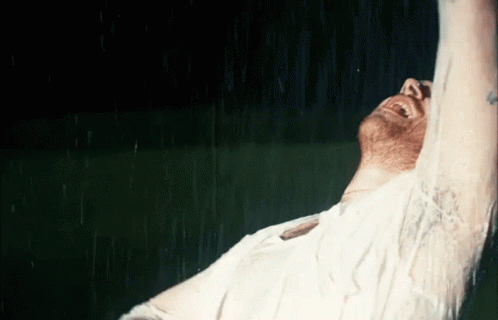 A Man In A White Shirt Is Laughing In The Rain GIF