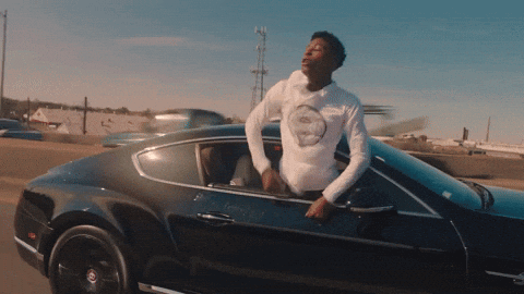 A Man In A White Shirt Is Leaning Out Of The Window Of A Black Car GIF