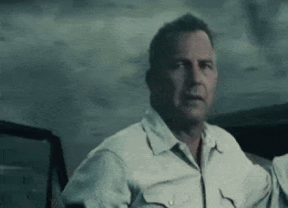 A Man In A White Shirt Is Looking Out Of A Car Window . GIF